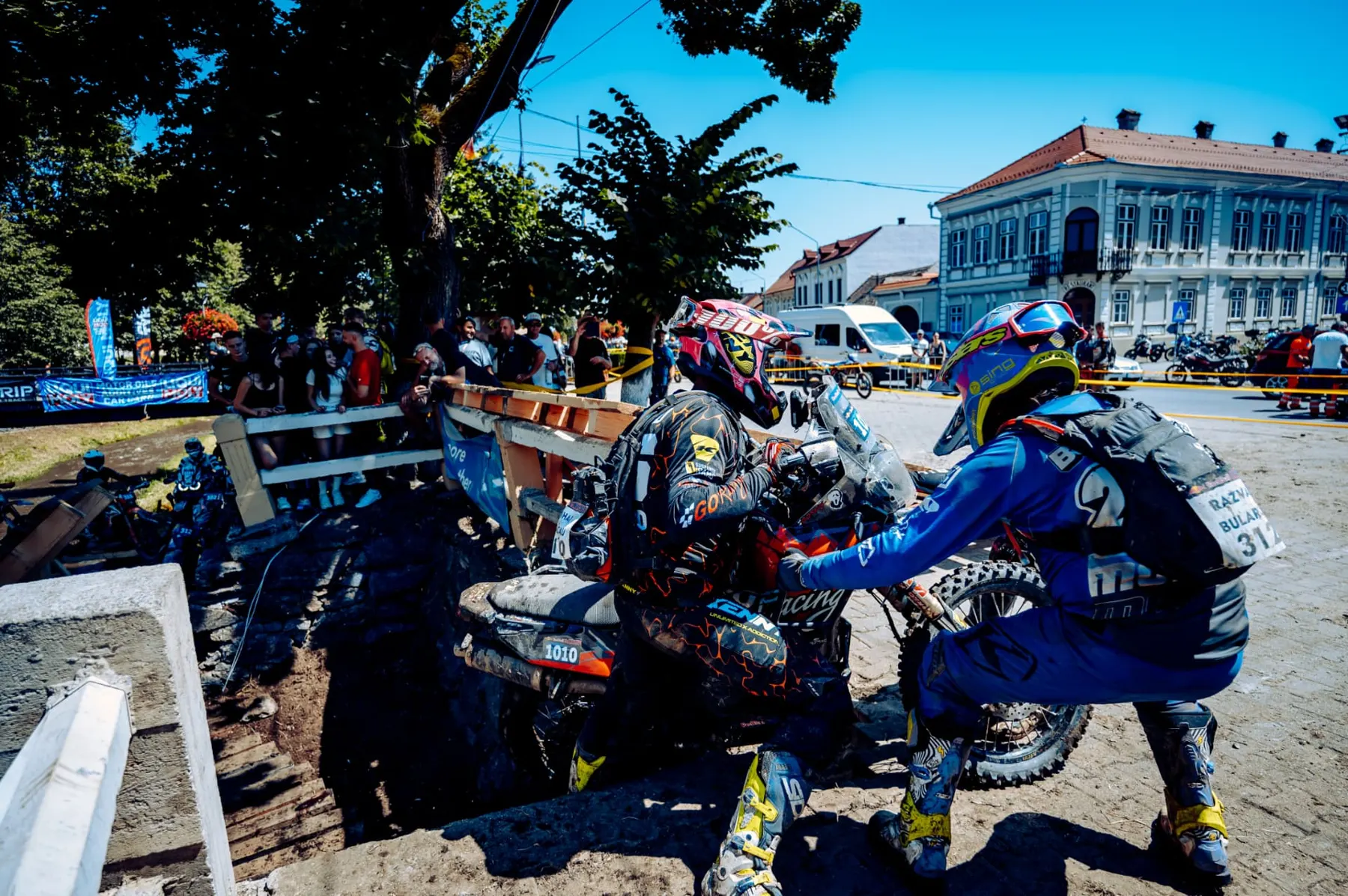 Riders working on a bike together beside a town street