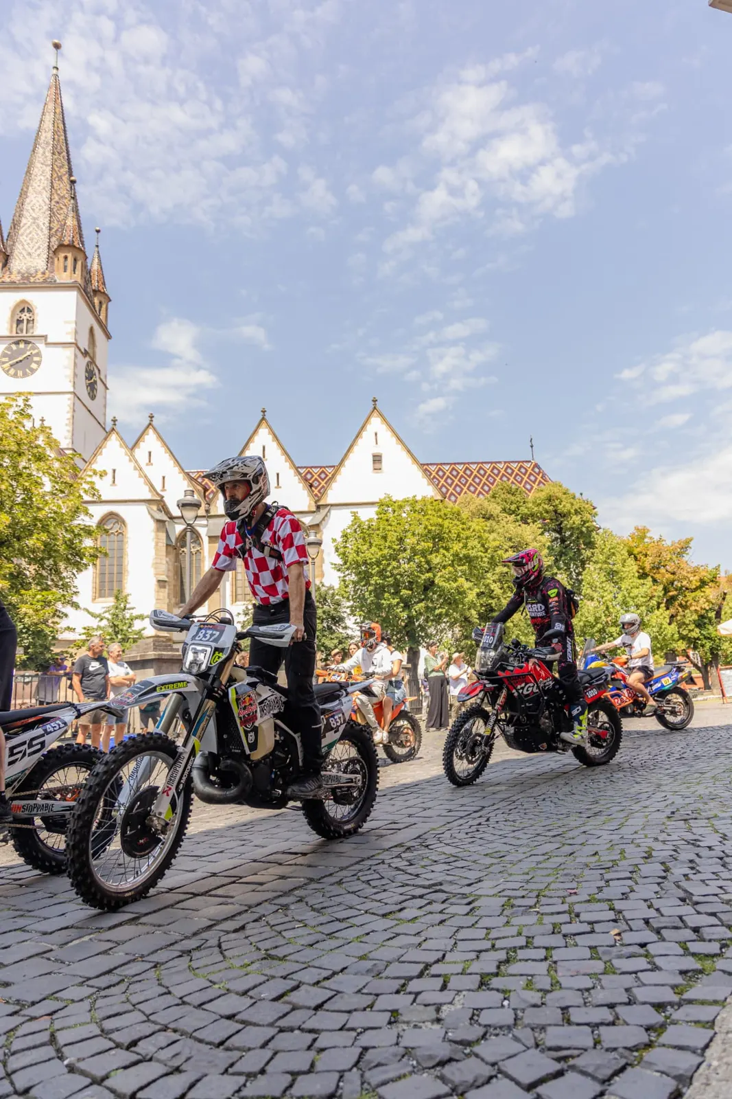 Riders on cobblestones in front of a historic church